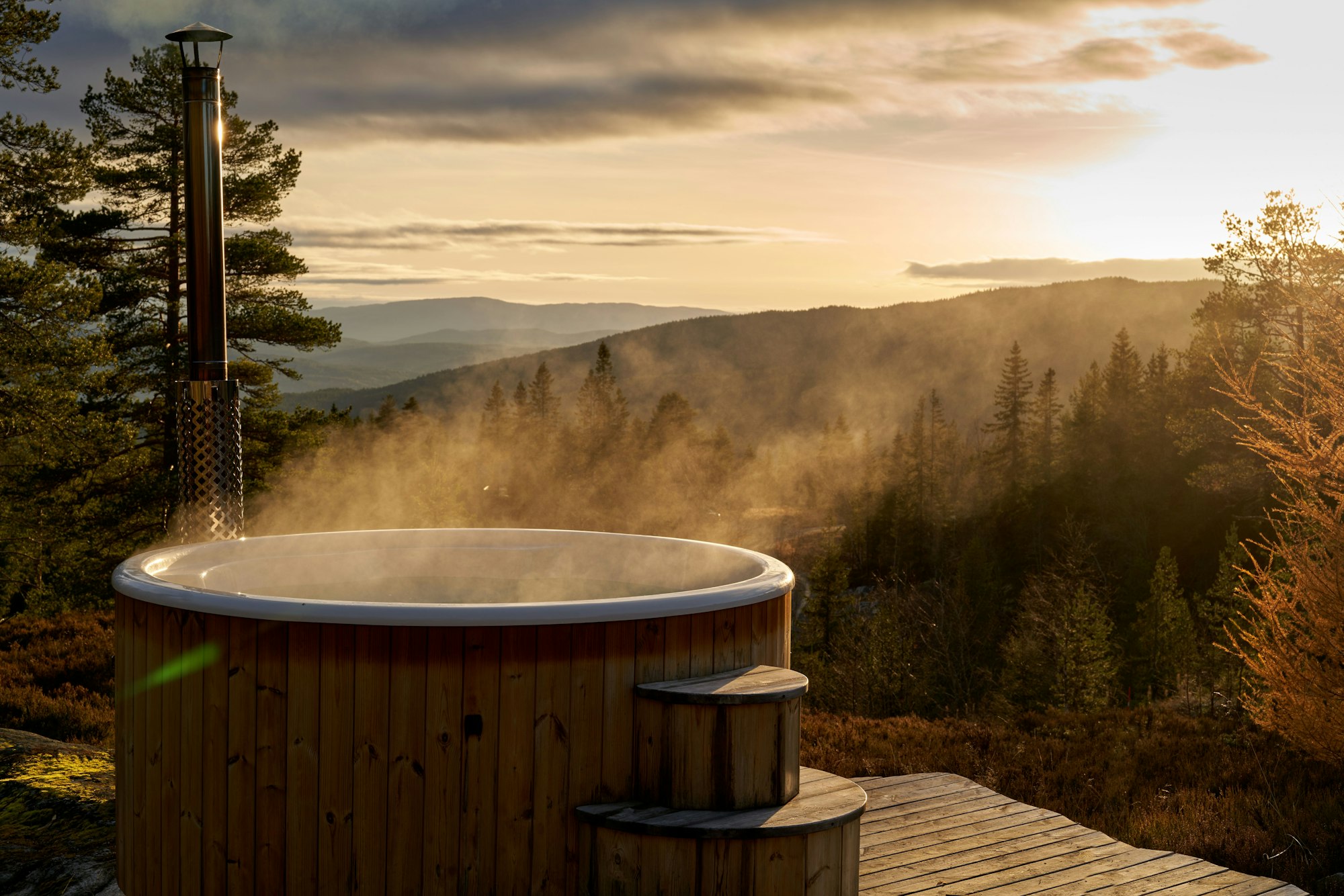 Wooden hot tub with scenic view to the valley in evening backlight